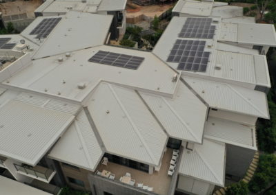 An aerial view of a roofing with solar panels on it.